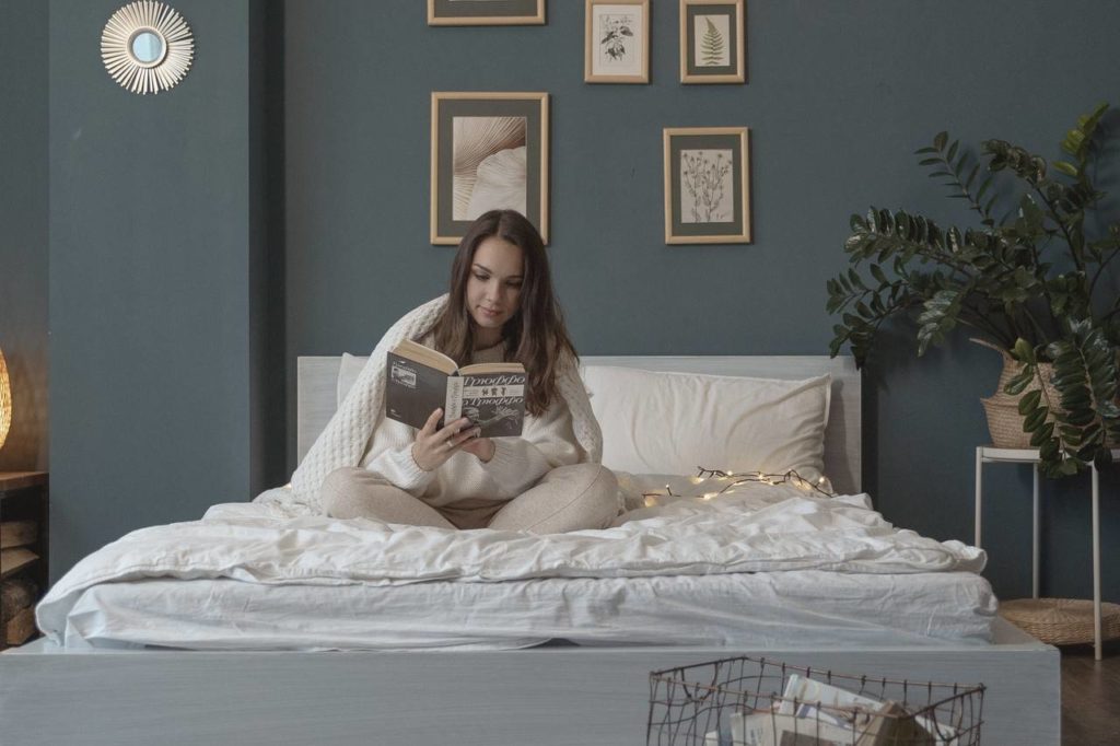mulher sentada na cama lendo um livro