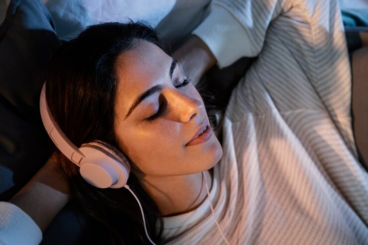 mulher-usando-fones-de-ouvido-para-musica-em-casa-na-cama - freepik