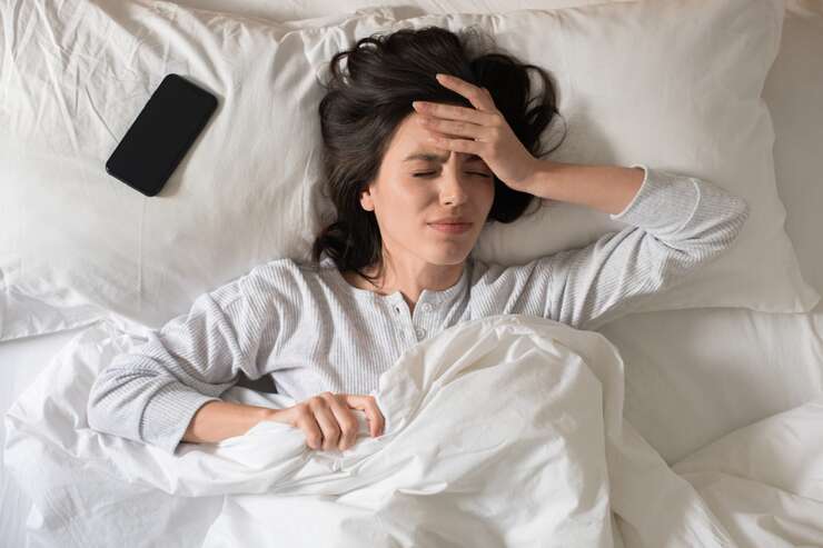 Mulher com dor de cabeça deitada na cama