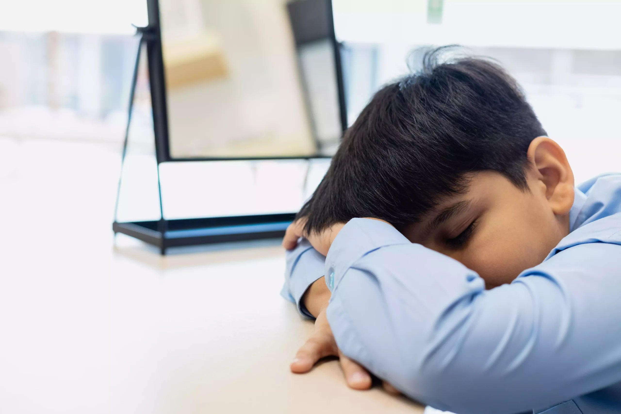 childboyfallsasleepattableclassroomkidpup20250309095140utc Menino dormindo em cima da mesa durante o dia