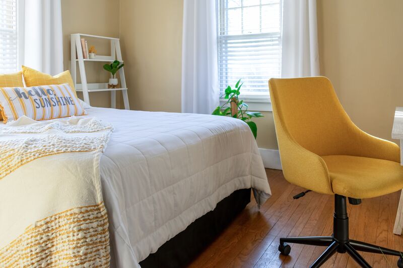Bedroom with stylish decor Quarto com a cama arrumada ao lado de uma cadeira