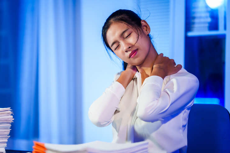 Mulher asiática acordando com dor no pescoço.