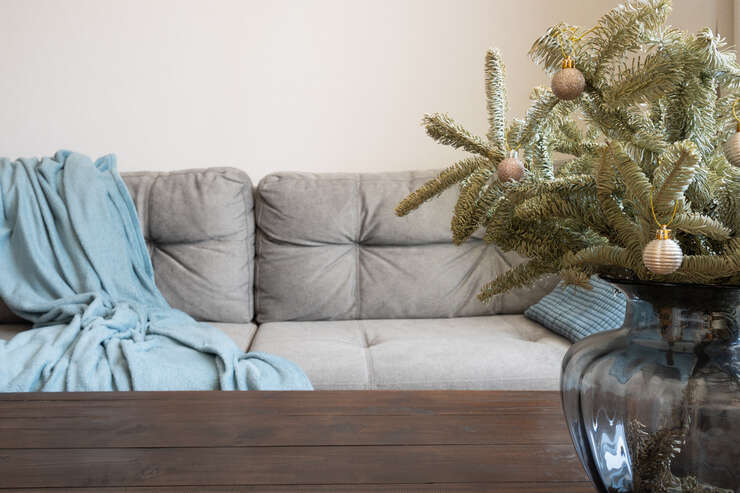 Blurred home interior in living room, decorated Christmas tree, wooden tabletop. sofa cinza com lençol em cima
