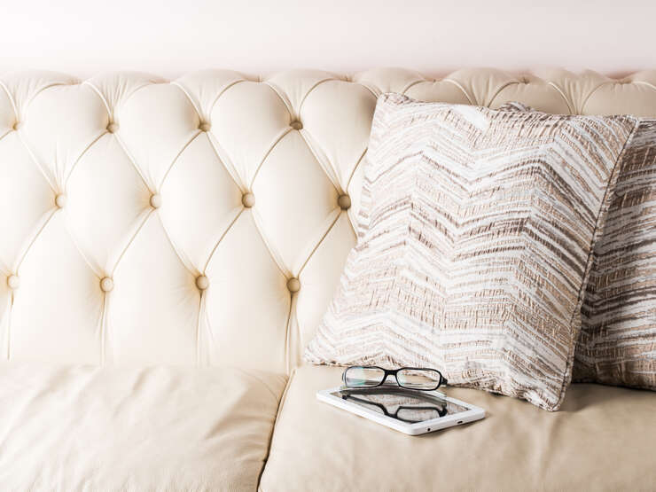 Glasses and white tablet on leather sofa Sofa branco com um livro e um oculos em cima do livro