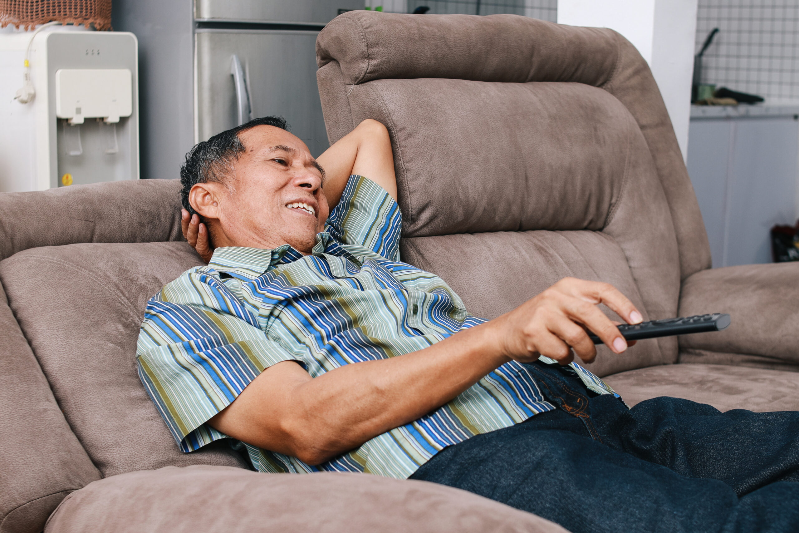 oldmanwatchingtv20250127110505utc Homem deitado no seu sofa assistindo tv.