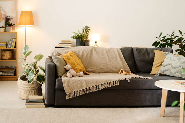 Part of couch in spacious living room sala de estar com sofa verde com lençol e travesseiro