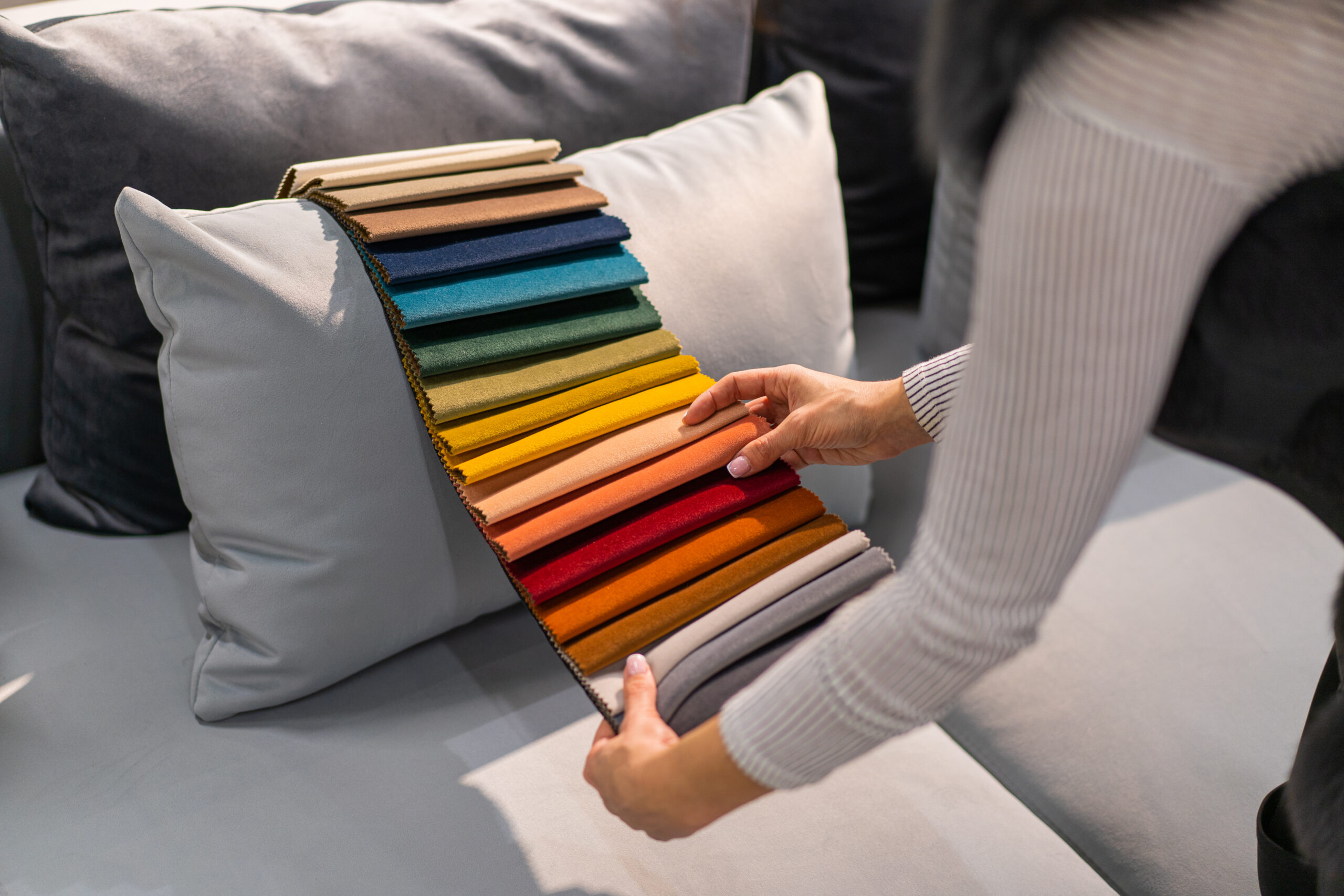 The woman chooses the fabric on the sofa. A young women looks at tissue samples. mulher olhando palhetas de cores para seu sofa