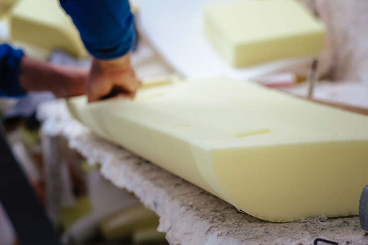 Vertical shot of a furniture maker shaping an upholstery foam homem mexendo com espumas de sofas