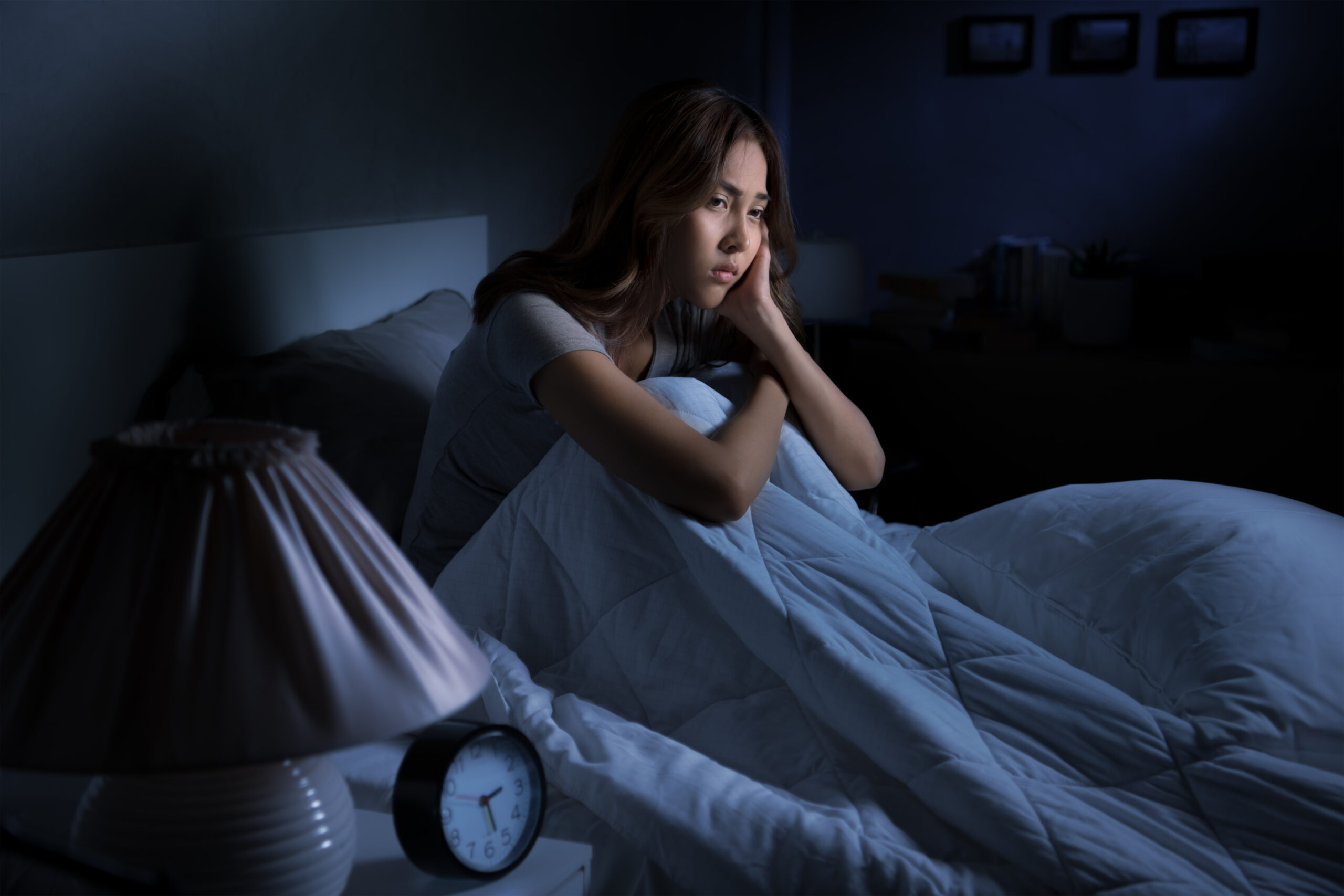 Depressed young Asian woman sitting in bed cannot sleep from insomnia Mulher sentada em cima da cama com insonia