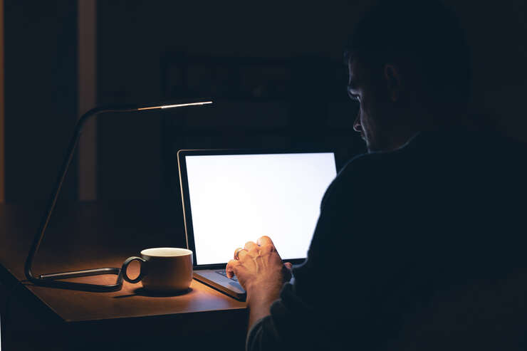 Homem mexendo no computador a noite