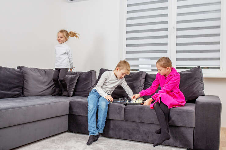 3 crianças brincando em sofa cinza