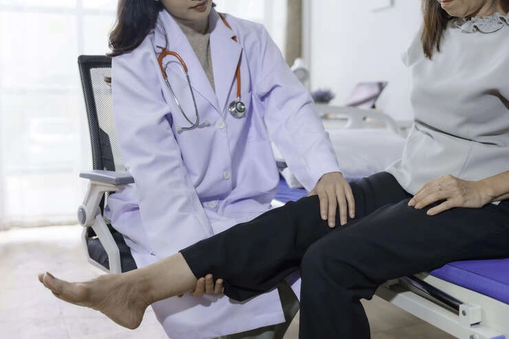 Medica analisando a perna de uma mulher.