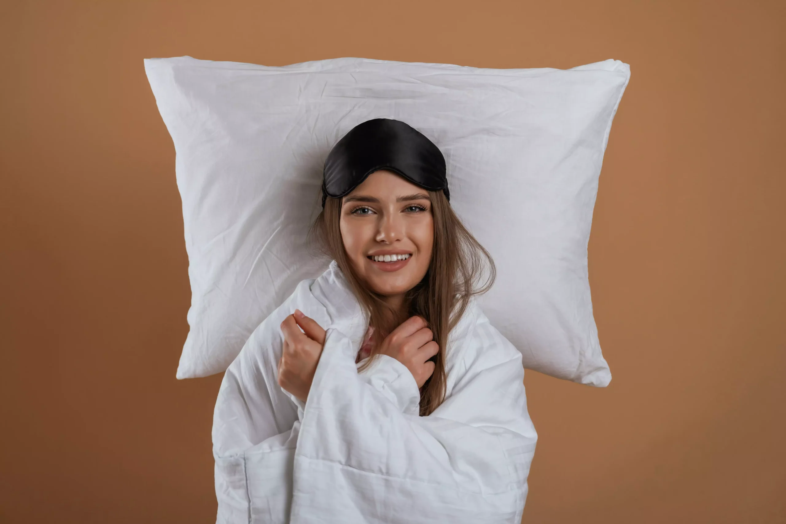 Mulher deitada no chão com travesseiro de baixo da cabeça sorrindo