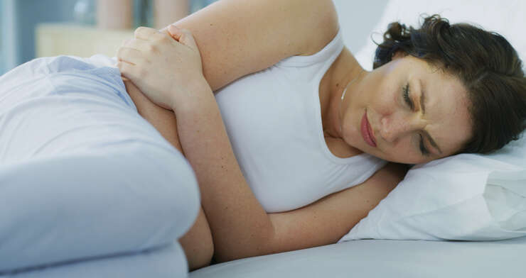 Mulher deitada de lado na cama se abracando