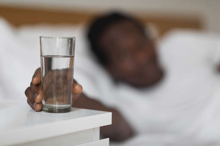 Homem deitado pegando 1 copo de agua