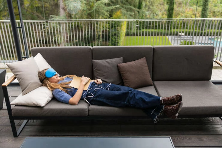 womanrelaxingonsofawithsleepmaskandtempera20250424230937utc Mulher deitada no sofa descansando.