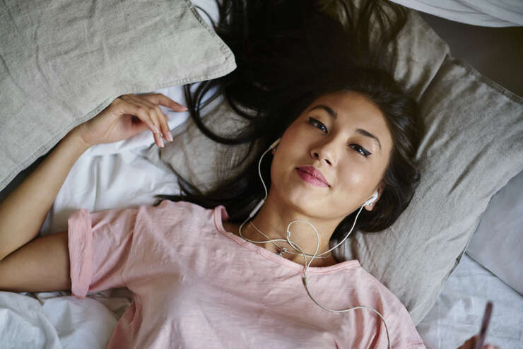 Mulher asiática deitada com fone de ouvido