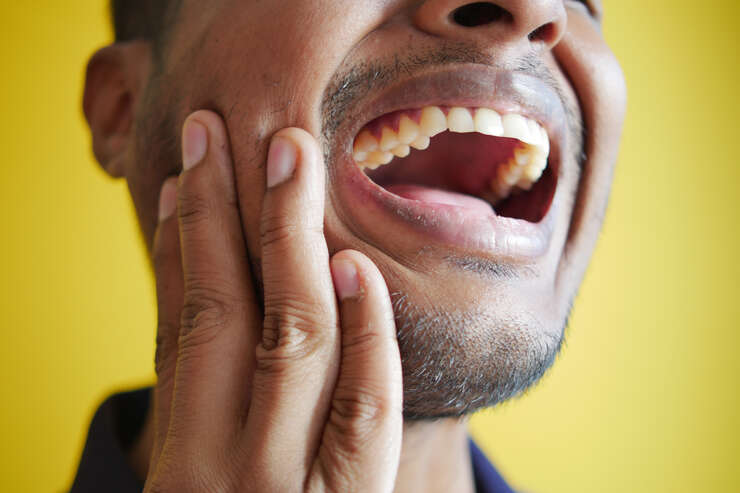 Homem com dor de dente em fundo amarelo