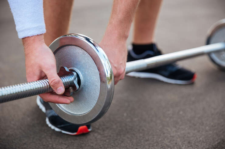 Pessoa levantando peso com barra na academia