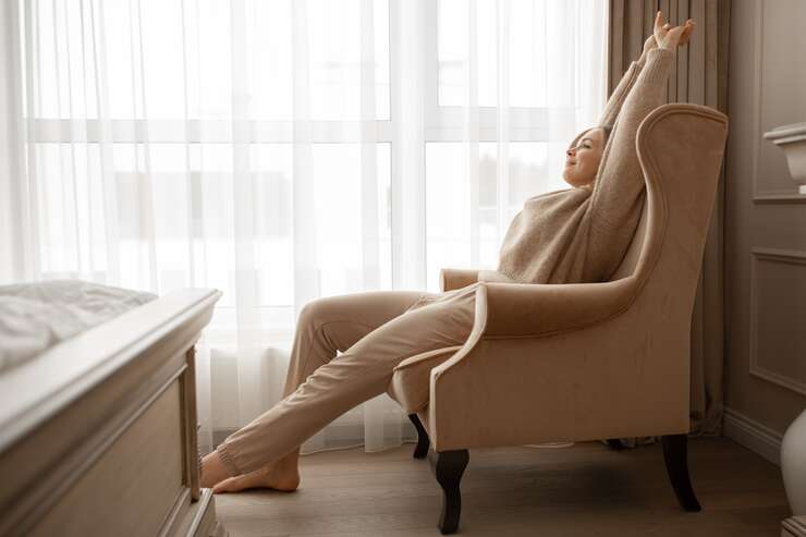 Mulher relaxando em uma poltrona ao lado da janela