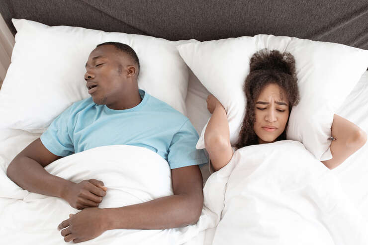 Casal dormindo, um homem snoring e mulher incomodada