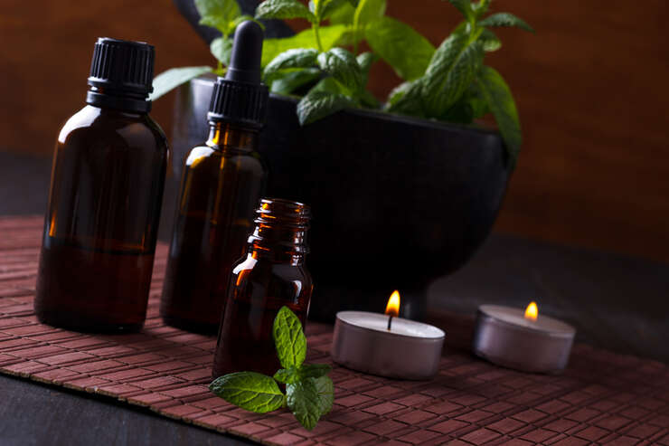 Frascos de óleos essenciais e velas com erva fresca.