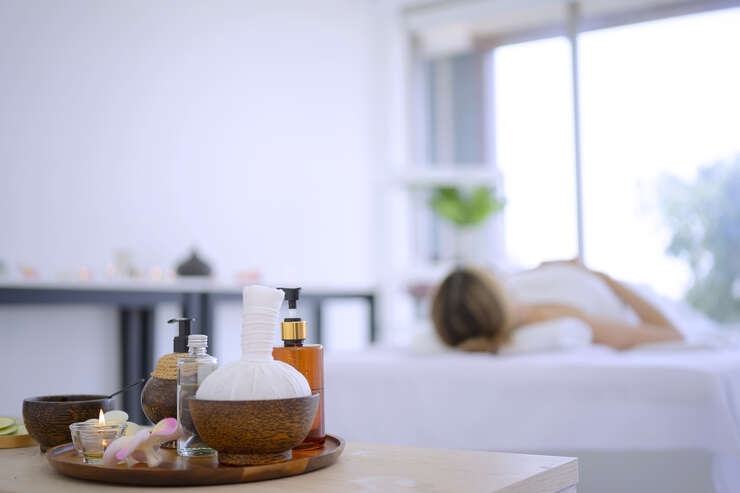 Produtos de spa em primeiro plano com massagem ao fundo