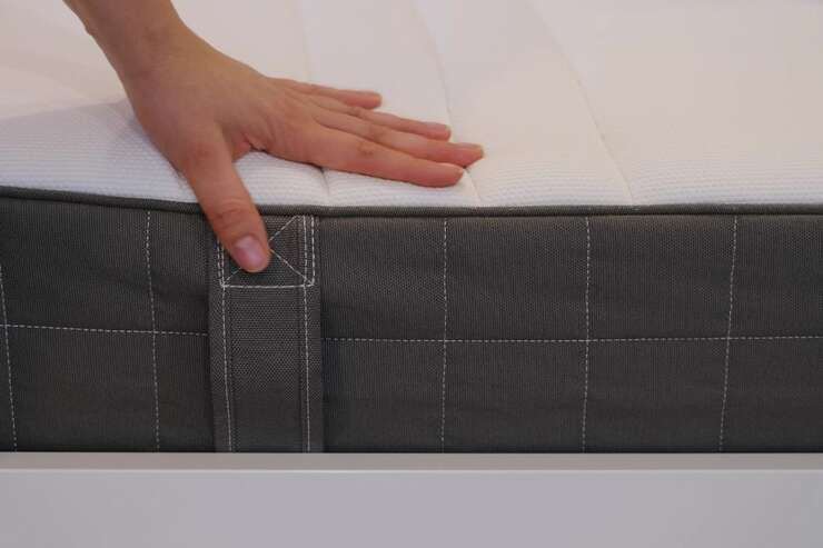 Pessoa ajustando colchão com superfície branca