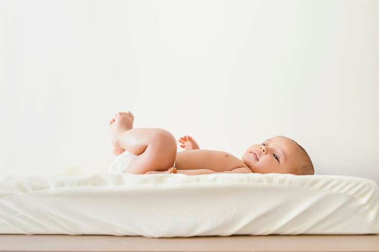 Bebê deitado em berço com lençol branco